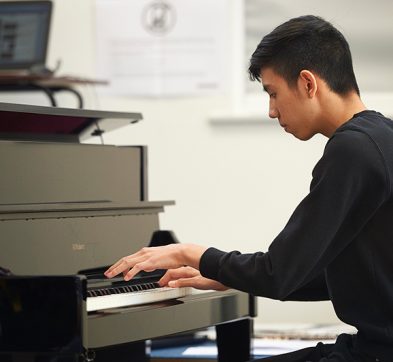 Abbey College Cambridge male student playing piano in the main hall