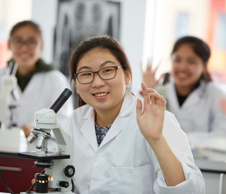 pupils in lab coats waving