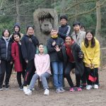 students posing by a chimpanzee statue