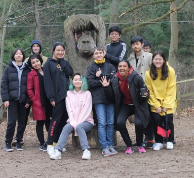 students posing by a chimpanzee statue