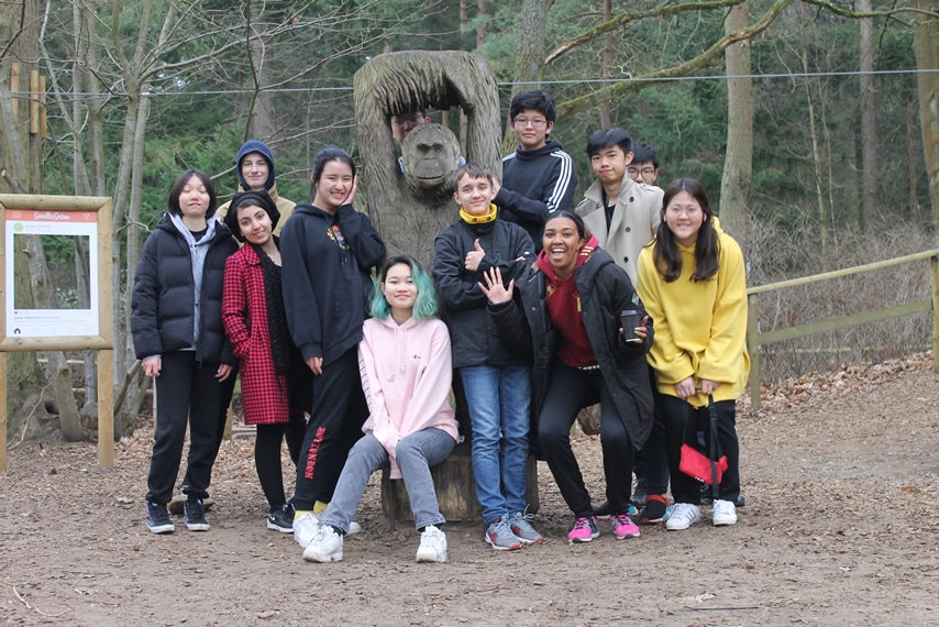 students posing by a chimpanzee statue