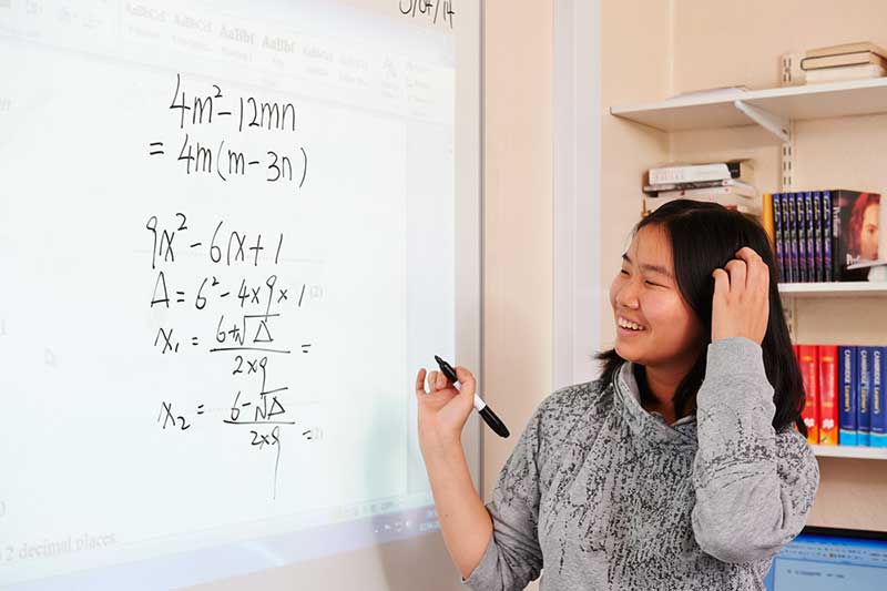 Student writing out maths equations on the whiteboard