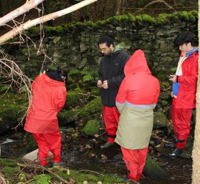 children wearing rain coats whilst measuring a river