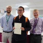 Student holding a certificate with two teachers either side