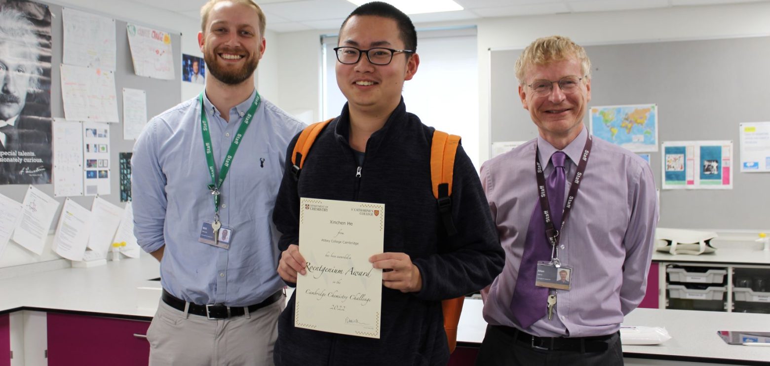 Student holding a certificate with two teachers either side