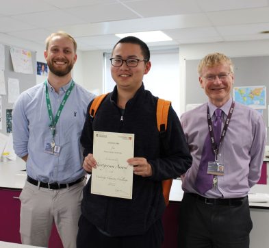 Student holding a certificate with two teachers either side
