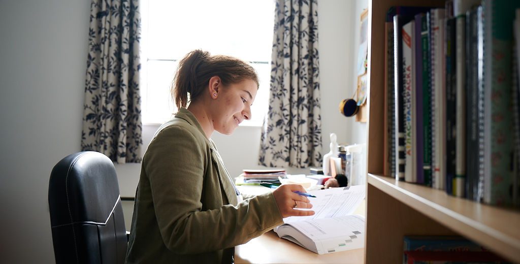 girl writing in a book by her desk