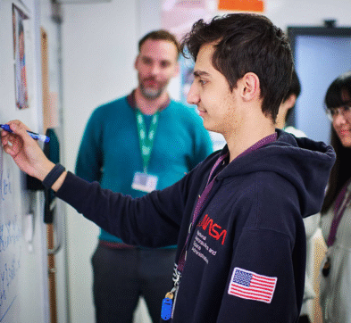 Student Writing On Whiteboard Wall In Maths Class At Abbey College Cambridge