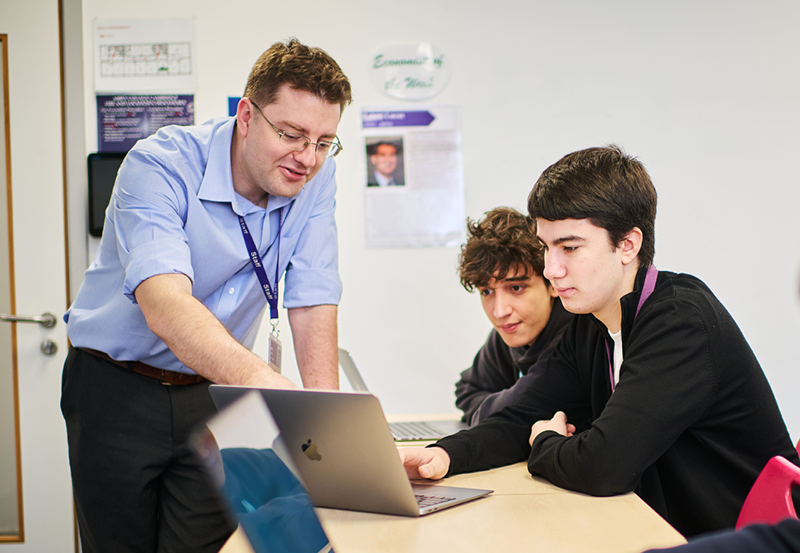 Teacher And Students Working In Economics Class